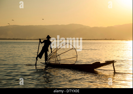 Fisherman nella luce della sera, gamba vogatore con un tradizionale cestello sul canoa, tramonto al Lago Inle, Stato Shan, Myanmar Foto Stock