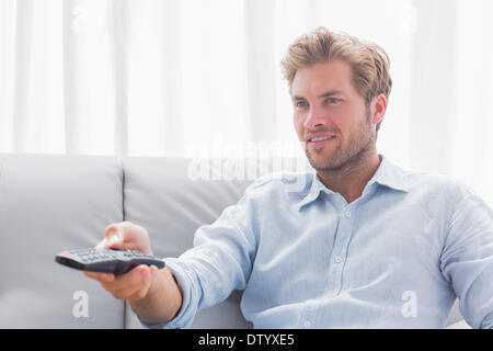 L'uomo cambiare canale tv sat sul lettino Foto Stock