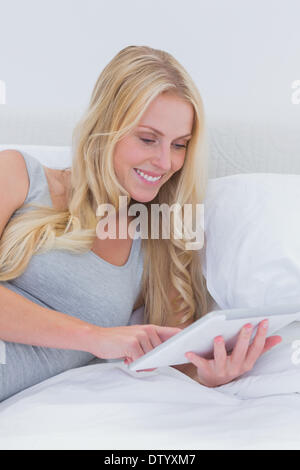 Donna allegra toccando il suo tablet a letto Foto Stock