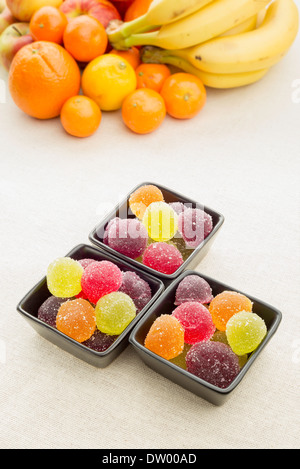 Colorato gelatine di frutta in little black tazze di ceramica. Frutti in background Foto Stock