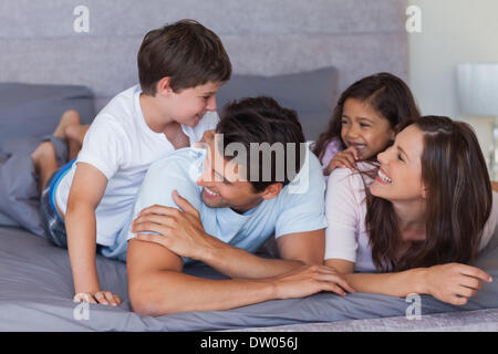 La famiglia felice avendo divertimento sul letto Foto Stock