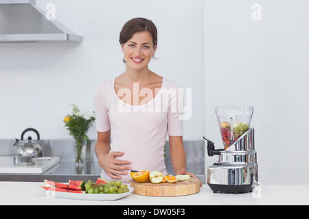 Donna incinta facendo un cocktail di frutta Foto Stock