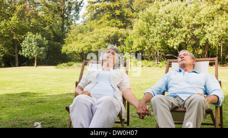 Coppia matura rilassarsi sui lettini per prendere il sole Foto Stock