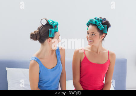 Le ragazze che indossano i capelli rulli seduta nel letto Foto Stock