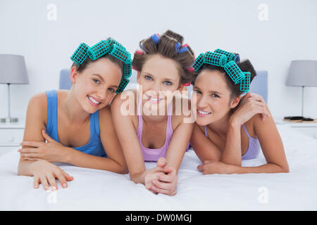 Ragazze in i capelli rulli giacente a letto Foto Stock