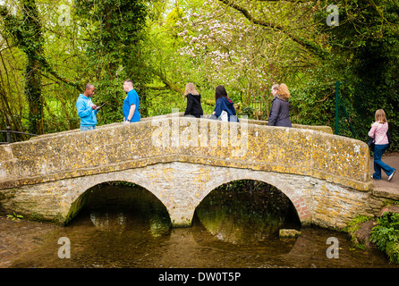Turisti attraversando il vecchio ponte in pietra a Lacock REGNO UNITO Foto Stock