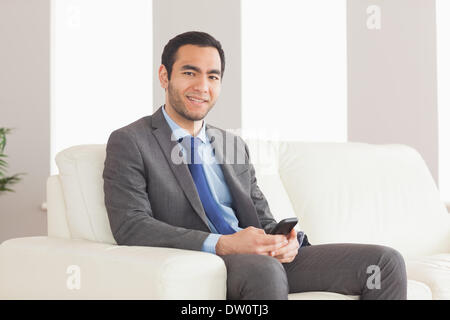 Imprenditore sorridente seduto sul divano accogliente Foto Stock