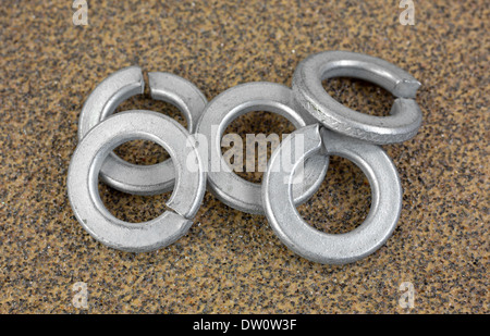 Un piccolo gruppo di acciaio o le rondelle di sicurezza su un pezzo di carta smerigliata a grana grossa. Foto Stock