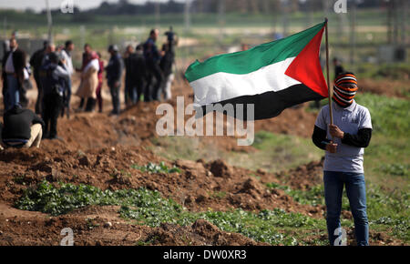 La striscia di Gaza, Territori palestinesi. 25 feb 2014. Un dimostrante palestinese getta indietro di un gas lacrimogeni canister come altri vengono eseguiti dal gas sparati dalle truppe israeliane nei pressi del confine israeliano recinzione tra Gaza e Israele nel nord della Striscia di Gaza, martedì 25 febbraio, 2014. Dimostranti palestinesi sono stati dell'anniversario di una moschea 1994 massacro quando un colono israeliano sparato e ucciso 29 per i fanatici musulmani nel centro della Cisgiordania città di Hebron. Credito: Majdi Fathi/NurPhoto/ZUMAPRESS.com/Alamy Live News Foto Stock