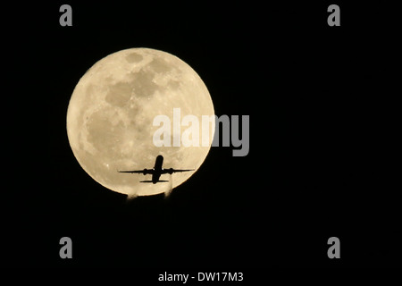 Commerciale aereo Jet passando davanti ad una luna piena- non reale Altered digitalmente Foto Stock