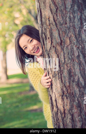 Donna nascondersi dietro a un albero Foto Stock