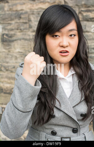 Arrabbiato donna da un muro di pietra Foto Stock