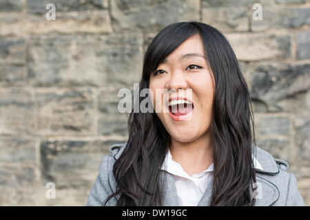 Donna che ride da un muro di pietra Foto Stock