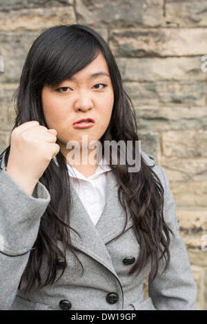 Arrabbiato donna da un muro di pietra Foto Stock