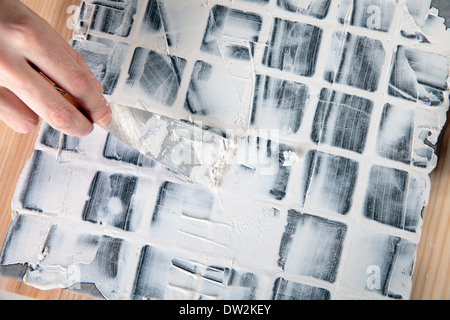 Lavoratore si applica boiacca a piastrelle grigie Foto Stock