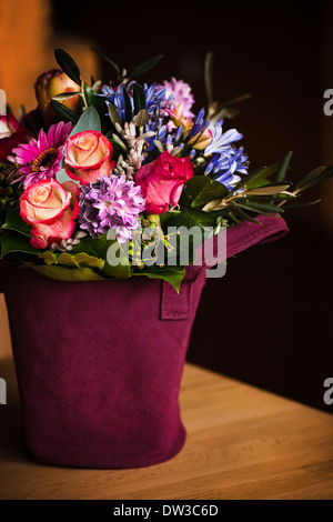 Vaso riempito con fiori di primavera e con un sfondo scuro su un tavolo Foto Stock