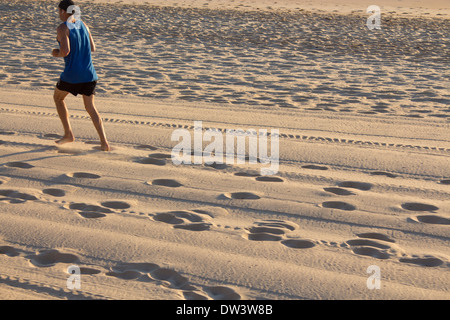 Impronte e tracce di pneumatici in sabbia all'alba con runner nell angolo in alto a sinistra del telaio del Nord Spiaggia Steyne Manly Sydney NSW Australia Foto Stock