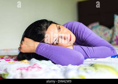 Triste donna sogna a occhi aperti e giacente in letto Foto Stock