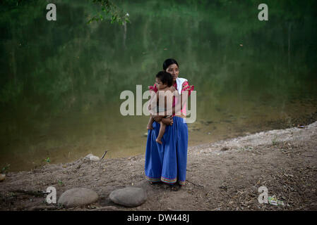 (140227) -- NGABE BUGLE REGIONE, 27 febbraio 2014 (Xinhua) -- una donna del Ngabe Bugle gruppo etnico porta il suo bambino in un campo vicino alla Tabasara fiume nella Ngabe Bugle regione indigeni, 450 km a ovest della città di Panama, capitale di Panama, nel febbraio 24, 2014. Il Ngabe Bugle regione indigena è situato nella zona occidentale di Panama e copre un'area di 6,968 km quadrati, con il 91 per cento della sua popolazione vive in condizioni di estrema povertà. Leader nativo del Ngabe Bugle regione dichiarata " nazionale alert', a causa dell'avviso di sfratto rilasciato da una società che sta sviluppando la hydro-electric proj Foto Stock