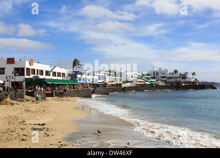 Piccola spiaggia di sabbia e la passeggiata sul lungomare con ristoranti in Playa Blanca, Lanzarote, Isole Canarie, Spagna Foto Stock