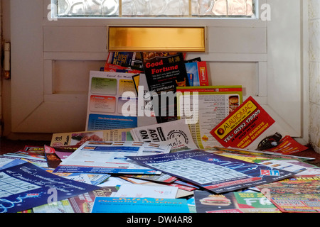 Un enorme pila di posta indesiderata che è stato messo attraverso la cassetta delle lettere di una porta anteriore Foto Stock