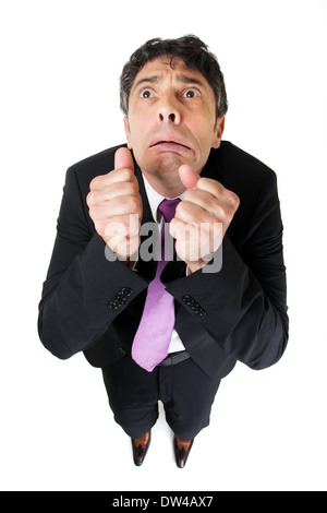 Comic high angle portrait of a middle-aged businessman with a scared fearful expression raising his fists to his face Foto Stock