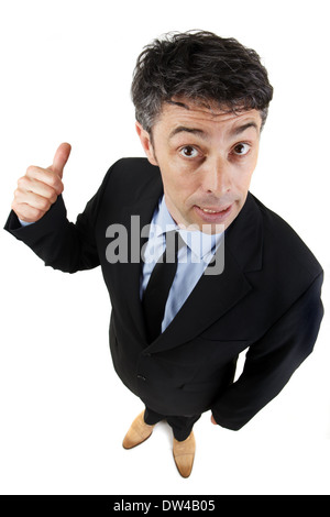 Imprenditore dando un pollice in alto gesto mentre dà alla telecamera un sorrisetto guardare a significare la sua approvazione, il successo o il conseguimento Foto Stock