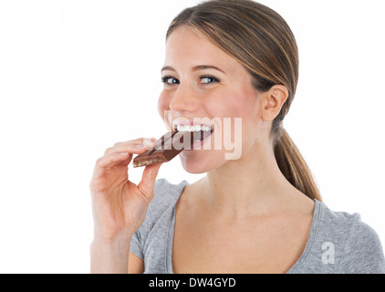 Ritratto di una giovane donna di mordere in una tavoletta di cioccolato, isolato su bianco Foto Stock