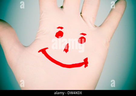 Sorriso disegnato su un guanto di plastica della mano. Reazione positiva contro la malattia. Foto Stock