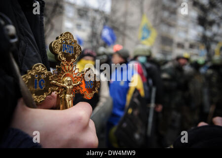 Un prete possiede un Crocifisso durante una manifestazione di protesta a Kiev (Ucraina), 14 febbraio 2014. Foto Stock