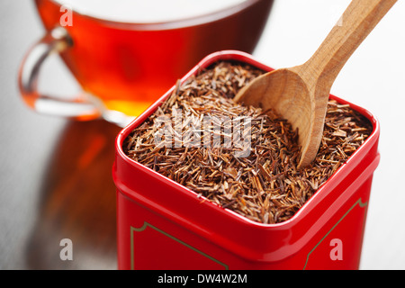 Rooibos nel tè la scatola di stagno e il cucchiaio di legno in primo piano Foto Stock