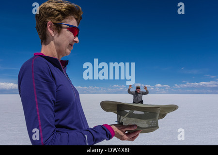 Due persone di eseguire una divertente prospettiva forzata che rende uno di essi vengono visualizzati piccoli e gli altri grandi del Salar de Uyuni. Foto Stock