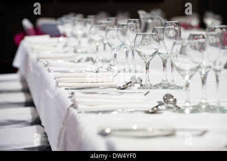 Una messa a fuoco poco profonda immagine del banchetto tabelle inserire le impostazioni e bicchieri di vino in attesa dell'arrivo delle cene di lavoro Foto Stock