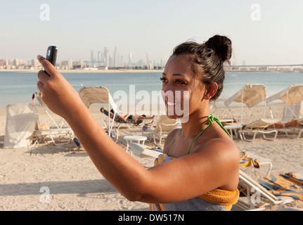 Donna prendendo una foto selfie sulla spiaggia in vacanza, Atlantis Hotel beach, Dubai Emirati Arabi Uniti, Emirati arabi del Medio Oriente Foto Stock