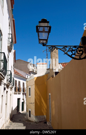 Tipico vicolo nel quartiere di Alfama, Lisbona, Portogallo. Strade strette e tortuose, con architettura dai colori rosso e sui tetti della città. Foto Stock