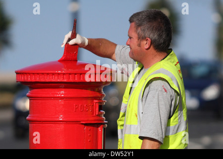 Un lavoratore dipinge un royal mail casella di invio Foto Stock