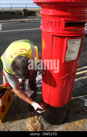 Un lavoratore dipinge un royal mail casella di invio Foto Stock