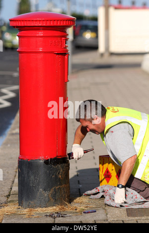 Un lavoratore dipinge un royal mail casella di invio Foto Stock