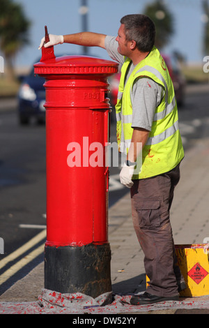 Un lavoratore dipinge un royal mail casella di invio Foto Stock