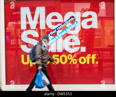 Un movimento sfocati shopper borse e zaini camminare davanti a un negozio di vendita al dettaglio la finestra di visualizzazione con un grande rosso vendita pubblicità segno sconto Foto Stock
