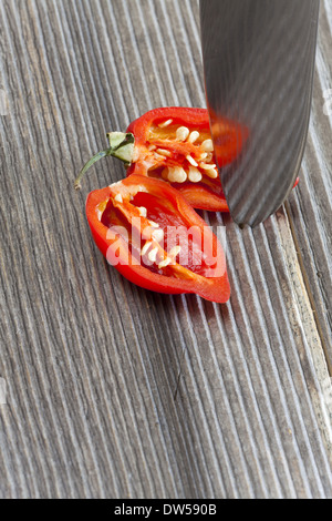 Fette di red hot habanero peperoncino in due metà con un coltello da cucina in legno rustico board Foto Stock