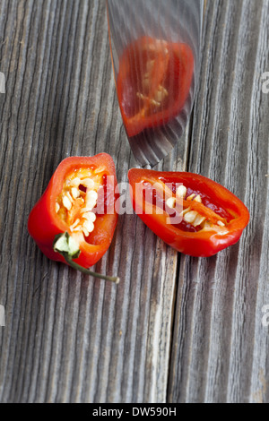 Due metà di un habanero peperoncino riflessa nella lama di un coltello da cucina Foto Stock