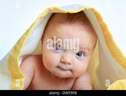 Baby girl sotto un bianco e giallo blanket, isolati su sfondo bianco Foto Stock