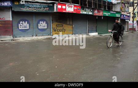 Srinagar, Indiano Kashmir amministrato. 28 Feb 2014 Un uomo pagaie la sua bicicletta accanto ai negozi chiusi durante uno sciopero a Srinagar, India, negozi e la creazione di imprese è rimasta chiusa in indiano-porzione controllata della disputa sul Kashmir come separatisti chiamato per uno sciopero generale esigenti sonda imparziale nella uccisione di sette sospetti ribelli uccisi dalle forze del governo in precedenza questa settimana.(Sofi Suhail/ Alamy Live News) Foto Stock