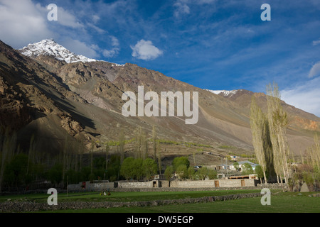 La gente del posto seduti fuori in settori al di fuori di un recinto murato, nel fiume Ghizar Gilgit (Fiume) valle vicino a Golaghmuli, visto dal Shandur-Gilgit Road, vicino al Shandur Pass, Gilgit-Baltistan, Pakistan Foto Stock