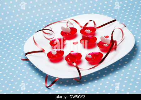 Piastra del giorno di San Valentino amore deserti di gelatina con il rosso e bianco cuori e nastro sul blu con puntini (polka dot) Contesto Foto Stock