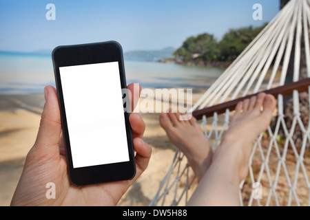 Smartphone in mano in spiaggia amaca