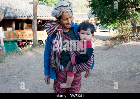 Karen Hill Tribe donna che porta il figlio in sling fermate per le foto in Blay Doh Key village, nel nord della Thailandia. Foto Stock