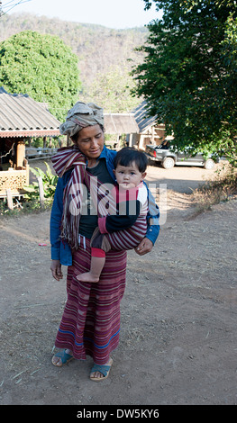 Karen Hill Tribe donna che porta il figlio in sling fermate per le foto in Blay Doh Key village, nel nord della Thailandia. Foto Stock