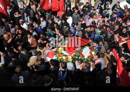 Birzeit, West Bank, Territorio palestinese. 28 feb 2014. Lutto palestinese portano il corpo di Mutaz Washaha, 22, un militante del Fronte Popolare per la liberazione della Palestina (PFLP), dalla Cisgiordania città di Birzeit, a nord di Ramallah, durante il suo funerale 28 febbraio 2014. Mutaz è stato ucciso dalle forze israeliane che presumibilmente utilizzato missili e bulldozer sulla sua casa il 27 febbraio 2014 Credit: Issam Rimawi APA/images/ZUMAPRESS.com/Alamy Live News Foto Stock